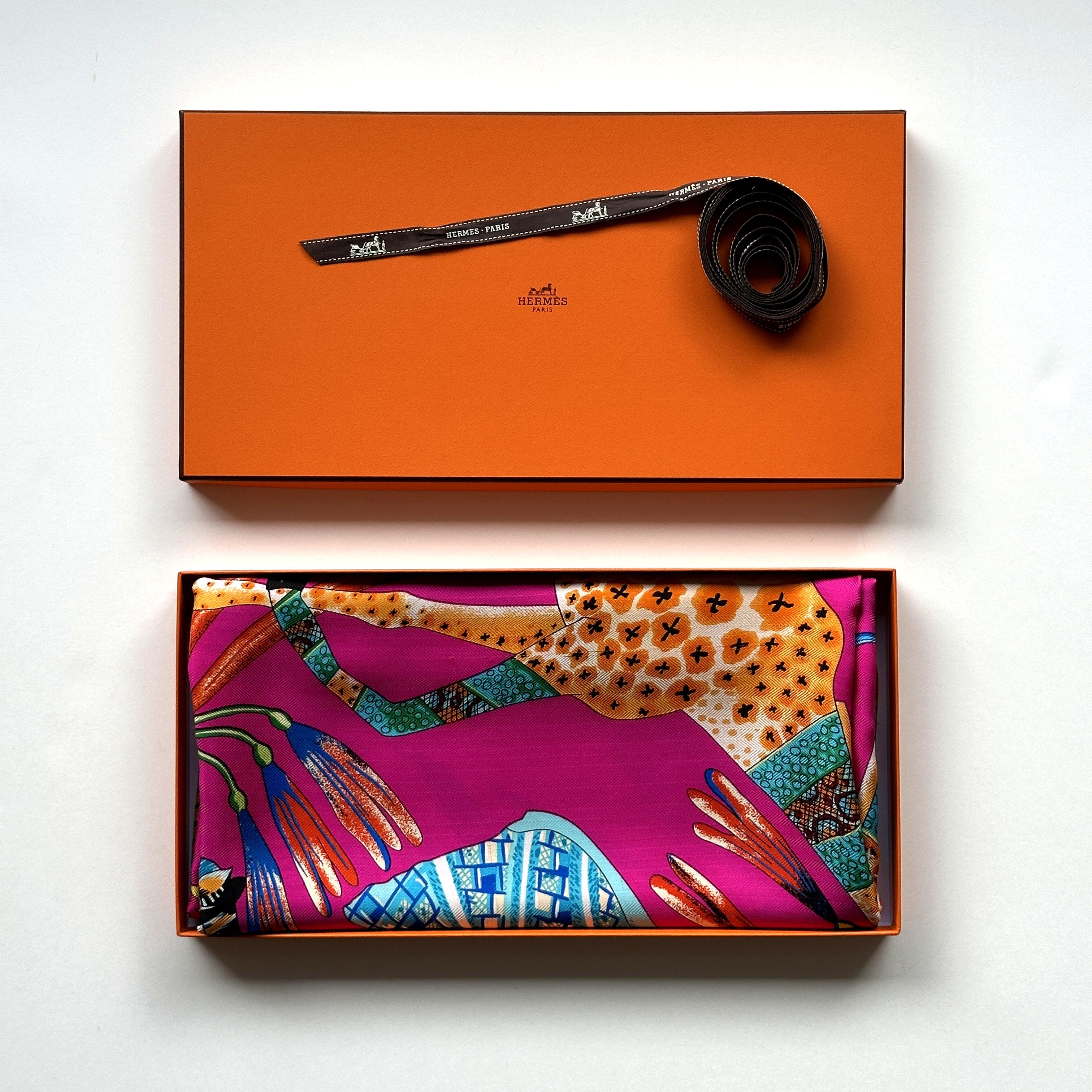 Carré Hermès La Marche du Zambèze 140 cm soie, présentation avec boîte Hermès orange et ruban