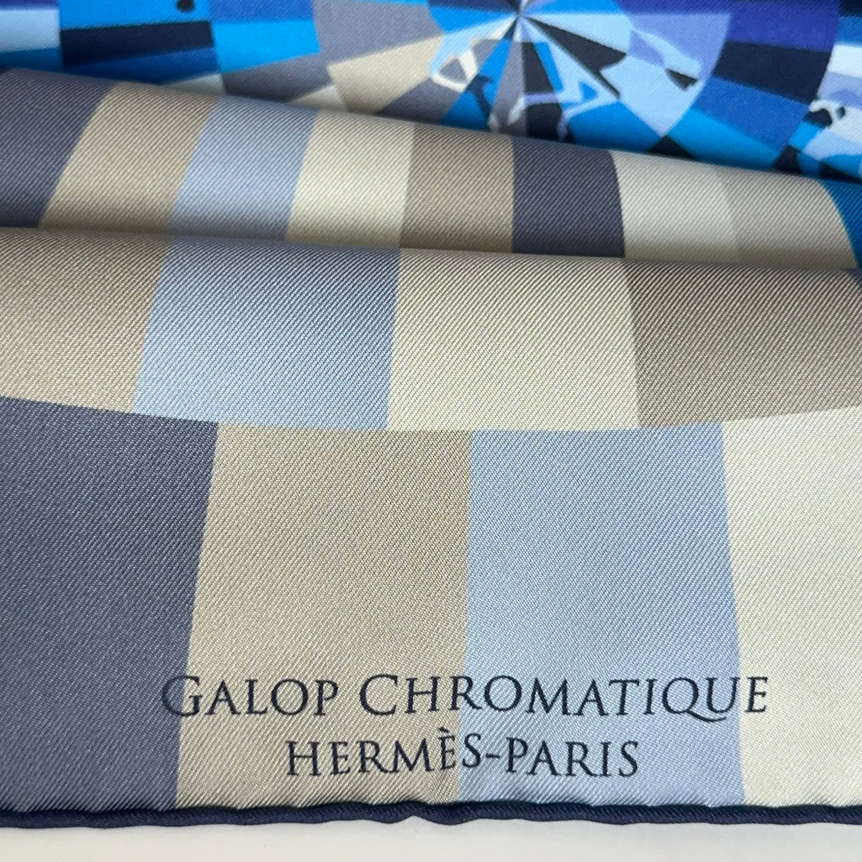 Titre du carré "GALOP CHROMATIQUE" imprimé en majuscules blanches sur une bande bleue contrastante en bas du foulard.