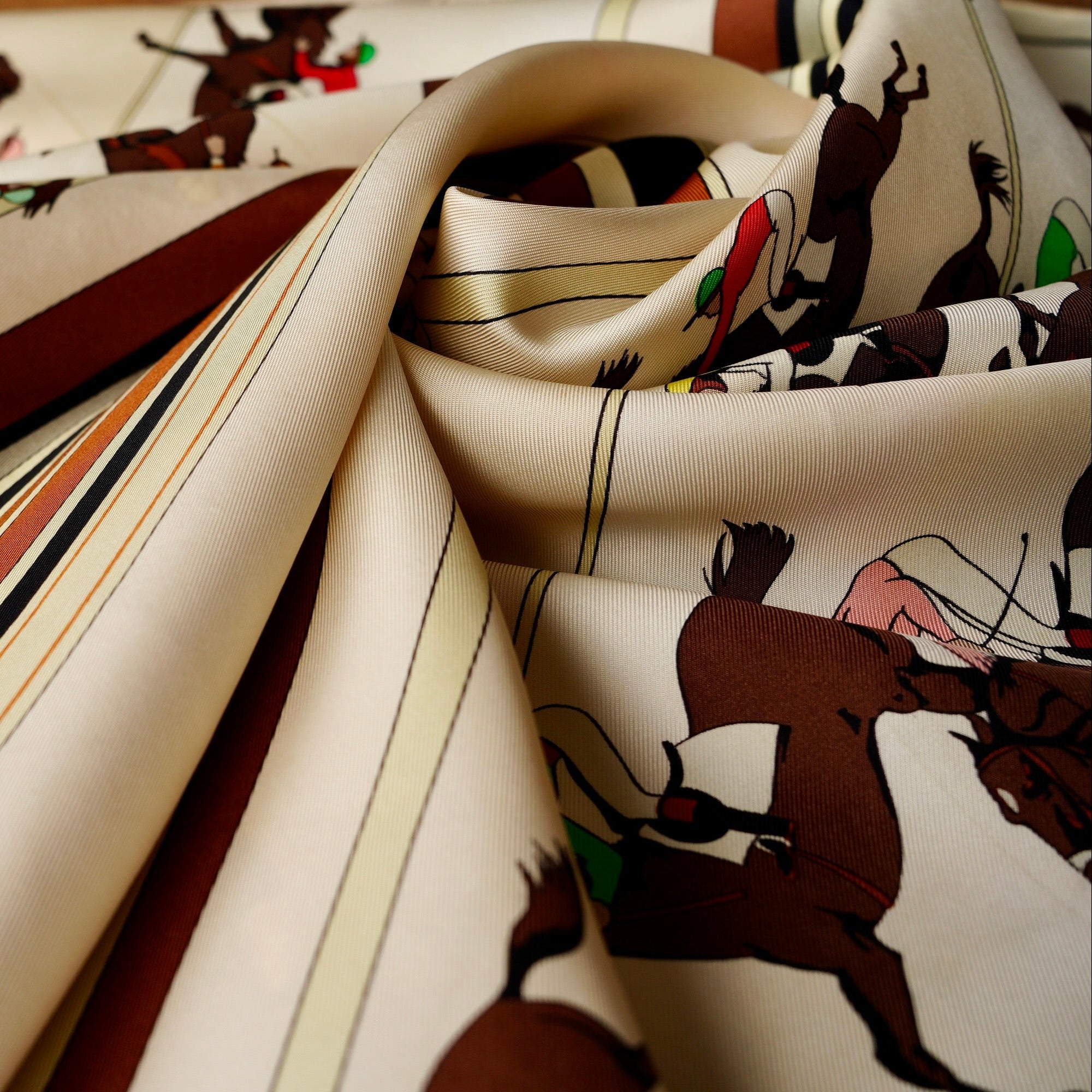 Zoom sur une section du foulard Hermès "Les Courses" avec flèches bleues indiquant de légères marques de pliure et traces d'usage.