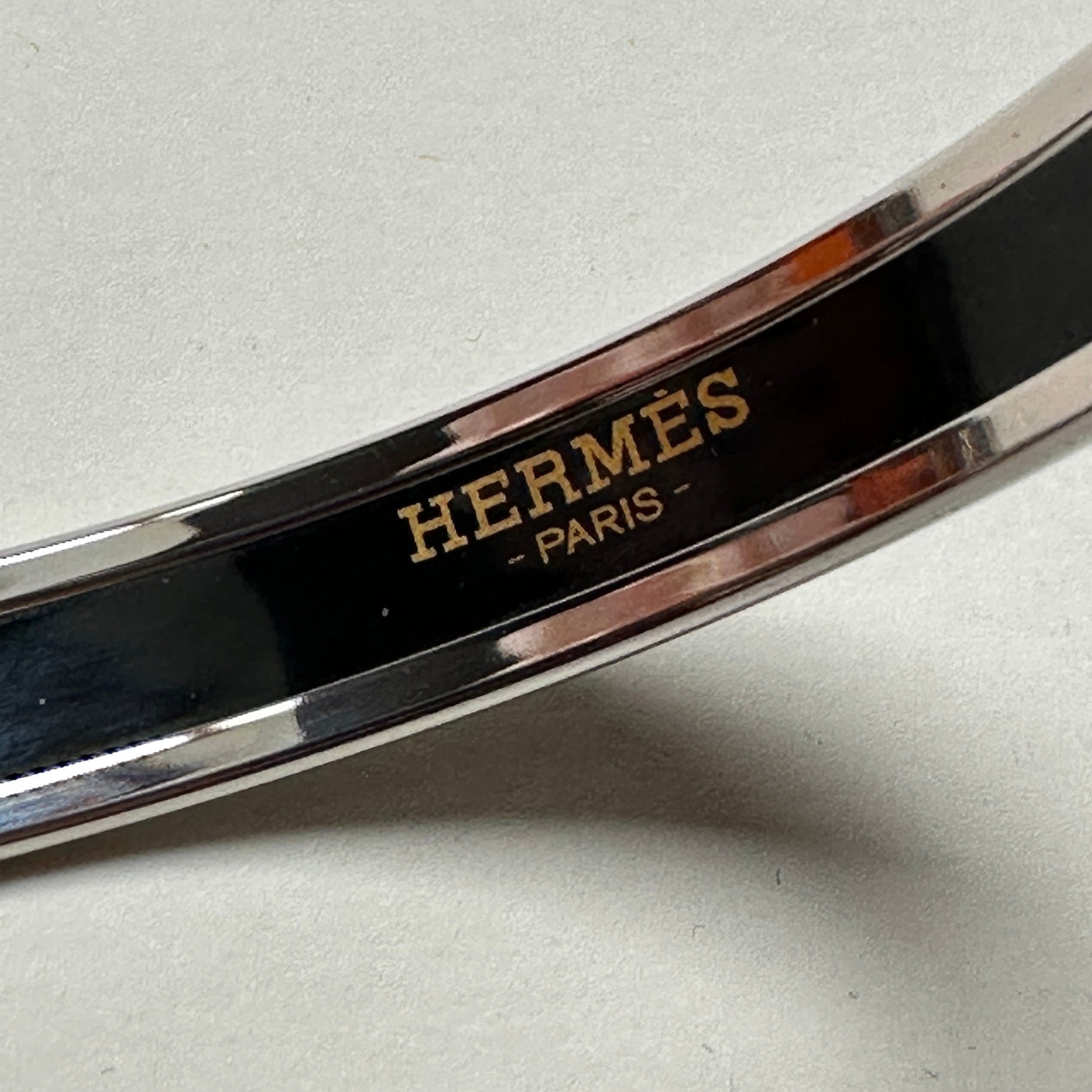 Logo "HERMÈS PARIS" gravé en lettres dorées à l'intérieur du bracelet jonc en émail noir.