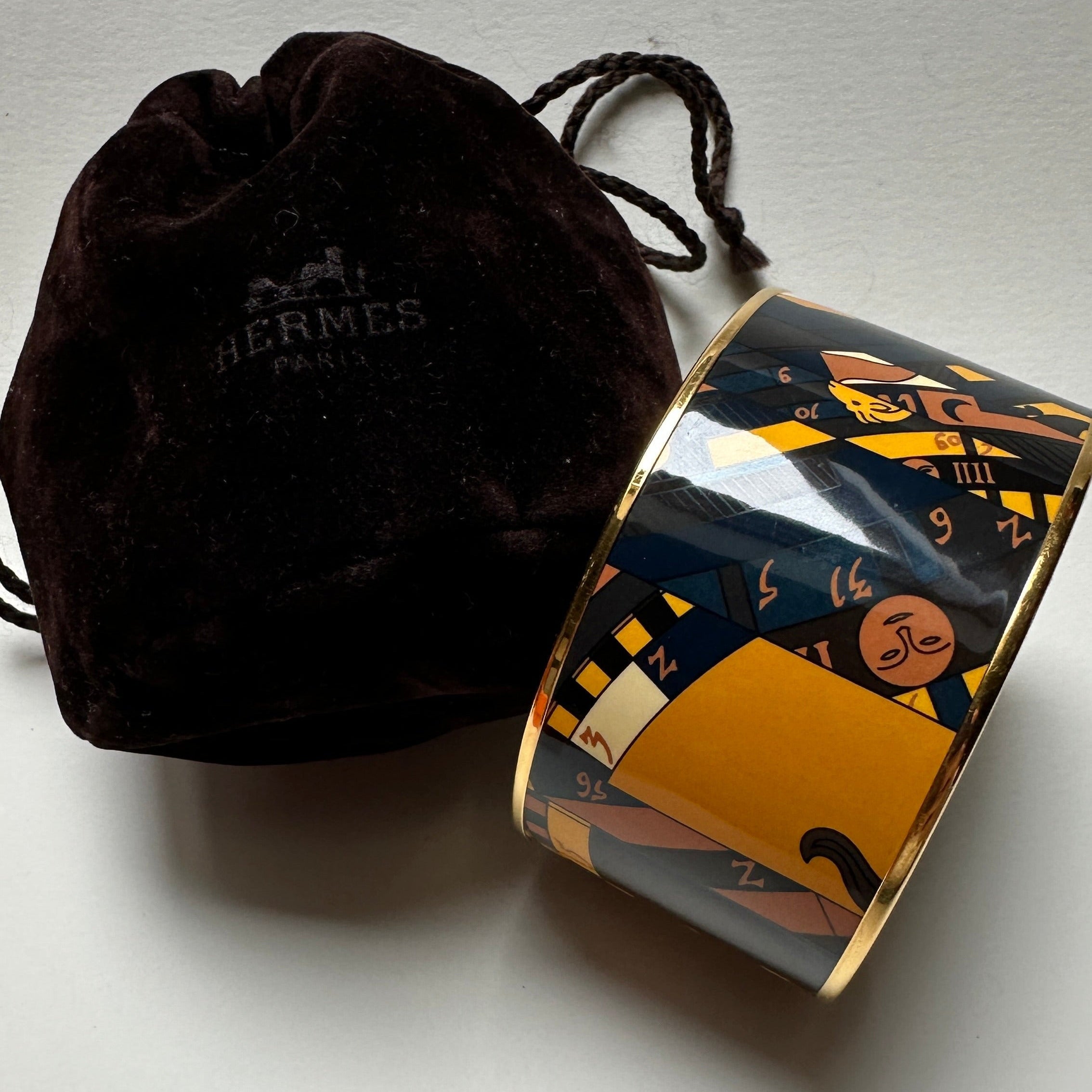 Manchette Hermès Astrologie Nouvelle émail présentée avec son pochon en velours