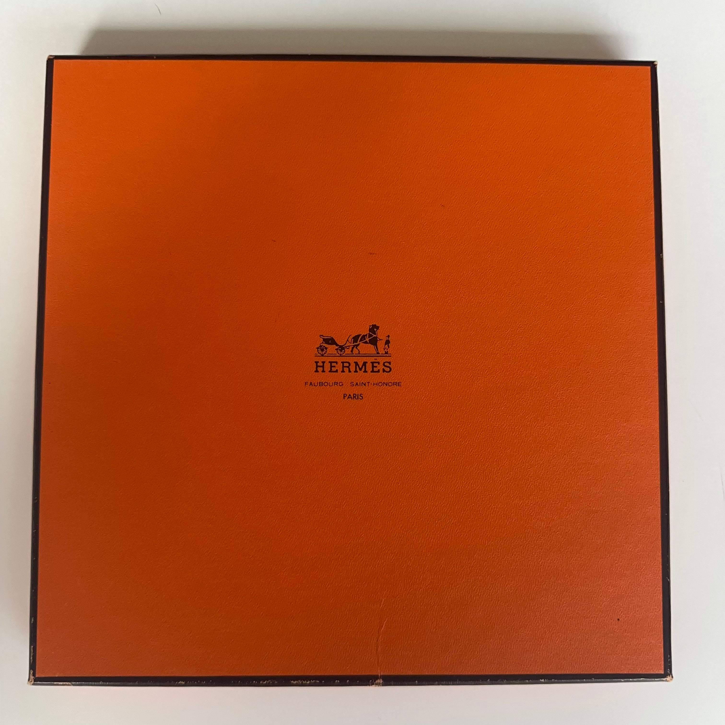 Vue de détail montrant les traces d'usure et petits défauts sur le couvercle de la boîte orange Hermès 