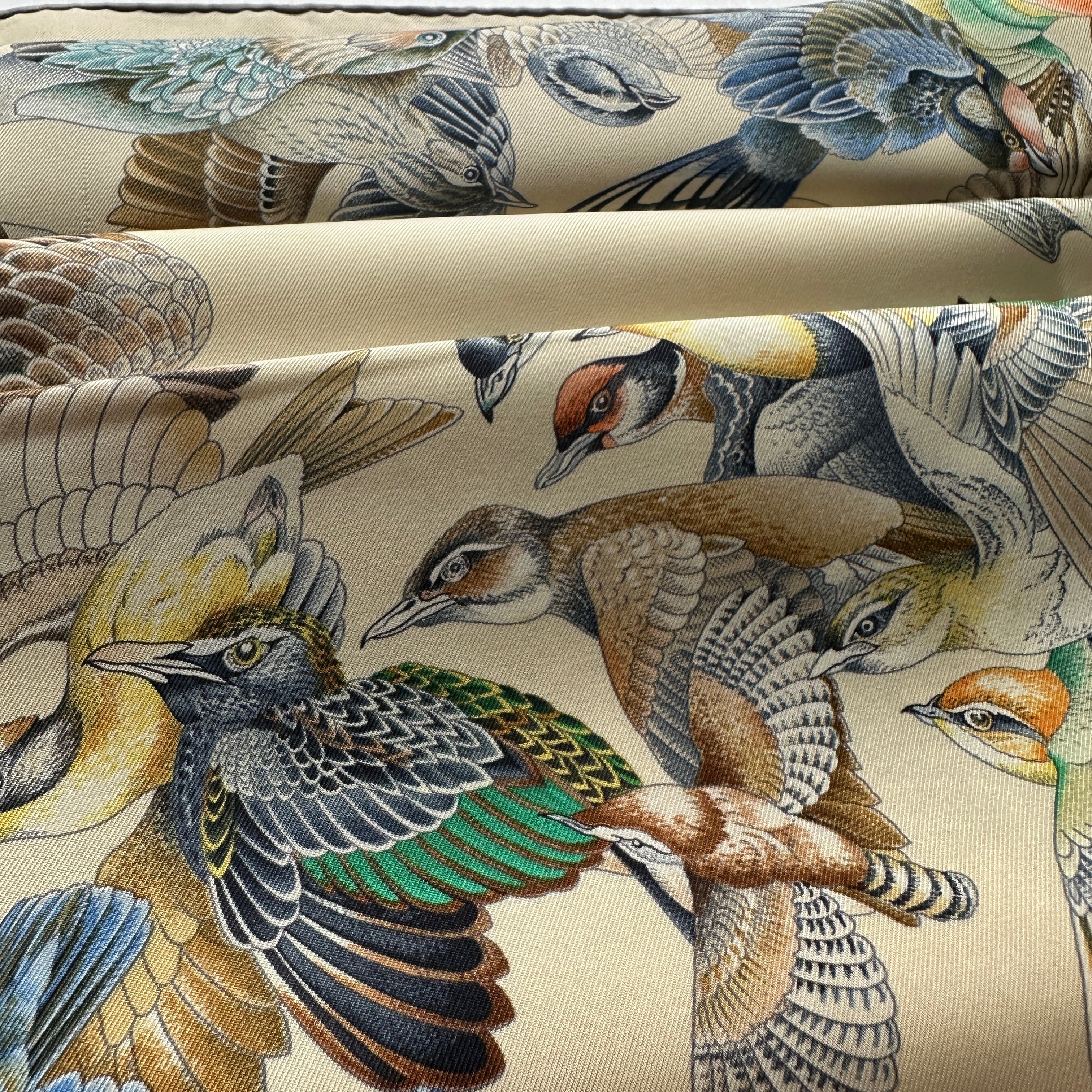 Vue artistique des plis du foulard montrant la qualité du twill de soie et la richesse des couleurs (or, bleu, rouille).