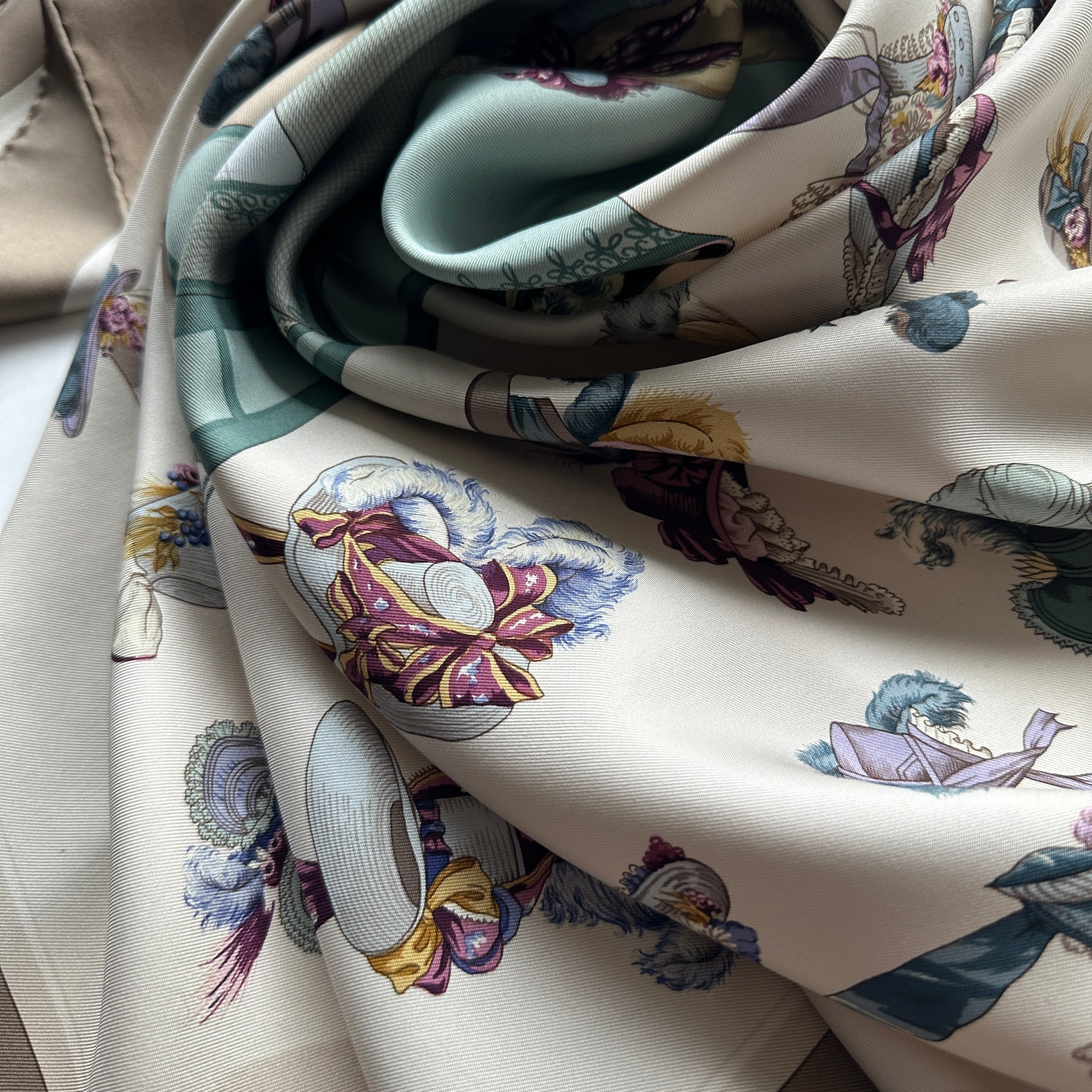 Le foulard Paris Modiste drapé artistiquement, montrant la fluidité de la soie vintage et les nuances de bleu, marron et crème.